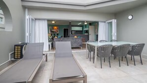 A modern interior with a dining area, a lounge area, and a kitchen visible through an open doorway. - Seaside Apartment @ Perna Perna Umdloti (eMdloti)