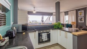 A modern kitchen with a central island, a built-in oven, and a view of the outdoors. - Seaside Apartment @ Perna Perna Umdloti (eMdloti)