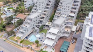 A high-rise residential building with multiple balconies, a swimming pool, and a gated entrance. - Seaside Apartment @ Perna Perna Umdloti (eMdloti)