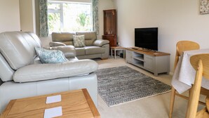 A living room with a sofa, a coffee table, a TV stand, and a dining area. - Tuliptree (Chesterfield)
