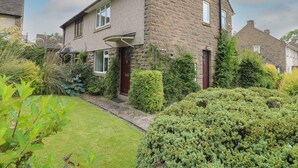 A two-story stone house with a front garden and a red door. - Tuliptree (Chesterfield)