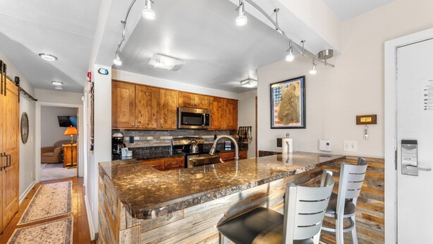 Una cocina moderna con armarios de madera, encimeras de granito y electrodomésticos de acero inoxidable.
