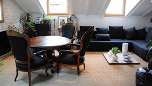 Un espacio habitable tipo loft con comedor, un sofá de color oscuro y un ventanal que proporciona luz natural.
