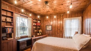 A cozy wooden room with a bed, a desk, and bookshelves.