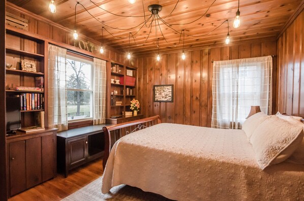A cozy wooden room with a bed, a desk, and bookshelves.