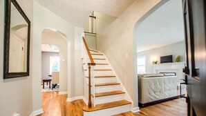 A staircase with wooden steps and a white handrail leading to a living area with a white sofa and a television.