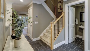 A home interior with a staircase, a potted plant, and a bathroom with a sink and mirror. - Sunset Rentals | Heritage Villas 2292 (Hilton Head Island)