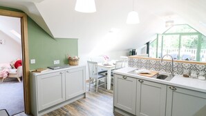 A modern kitchen with white cabinets, a wooden countertop, and pendant lighting. - Old Wood Coach House (Lincoln)