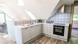 A modern kitchen with a sloped ceiling, built-in appliances, and patterned backsplash. - Old Wood Coach House (Lincoln)