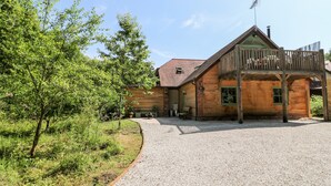 A wooden cabin with a gravel driveway and a wooden deck. - Old Wood Coach House (Lincoln)
