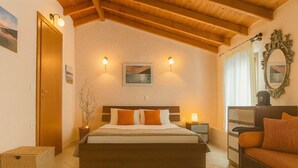 Une chambre avec un plafond en bois, un lit avec des oreillers, des lampes de chevet, une table de chevet, une commode, un miroir et une fenêtre avec des rideaux.