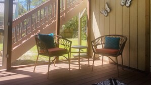 En inglasad veranda med två fåtöljer i rotting, ett litet bord och en trätrappa.