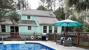 En swimmingpool med ett trädäck och ett hus i bakgrunden.