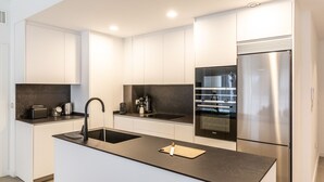 Une cuisine moderne dotée d’un îlot central, d’un four encastré et d’un réfrigérateur en acier inoxydable.