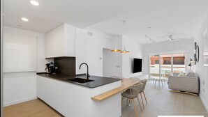 A modern kitchen with a central island, a dining area with a sofa and chairs, and a large window providing a view of the outside.