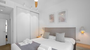 Ett modernt hotellrum med en stor säng, en garderob, ett nattduksbord och en takfläkt.