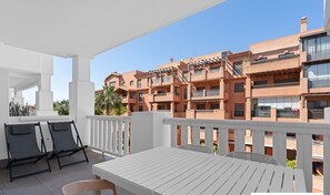 A balcony with a white table and chairs, overlooking a multi-story building with balconies. - Ref. 336891 (Motril)