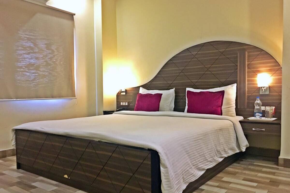 Habitació d'hotel amb un llit gran, dues taules de nit i un televisor fixat a la paret.