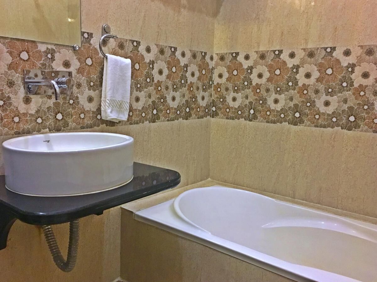 Un baño con un lavabo redondo, una bañera y un perchero para toallas.
