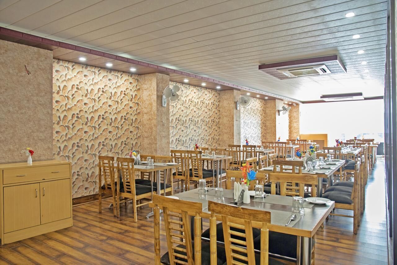 A spacious dining area with wooden tables and chairs, a patterned wall, and a wooden cabinet.