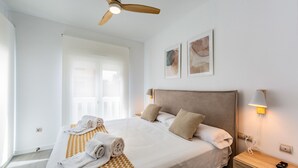 A hotel room with a bed, towels, a ceiling fan, wall-mounted artwork, and a bedside lamp. - Ref. 338306 (Motril)