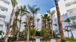 Un hotel moderno con un cortile centrale, palme e un elemento d'acqua.