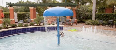 A pool with a blue umbrella, water jets, and lounge chairs.