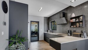 A modern kitchen with a large island, dark cabinetry, and a view into the dining area.