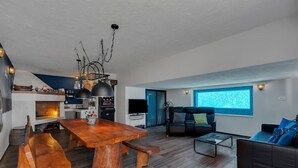 A modern living room with a wooden dining table, a sofa, and a television.