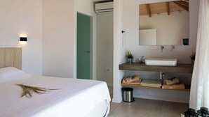 A modern bedroom with a bed, a bathroom with a sink, and a green door.