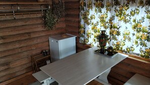 A rustic kitchen with wooden walls, a small refrigerator, a table, and a decorative vase. - Lomakoti kauniilla näkymillä Saimaan rannalla (Savonlinna)