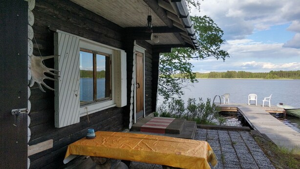 A wooden cabin with a table and chairs outside, overlooking a lake. - Lomakoti kauniilla näkymillä Saimaan rannalla (Savonlinna)