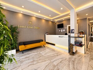 A reception area with a reception desk, a sofa, and a wall-mounted TV. - Livaneli Boutique Otel (Alanya)