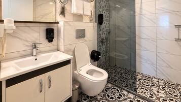 Un baño moderno con inodoro, lavabo y zona de ducha.
