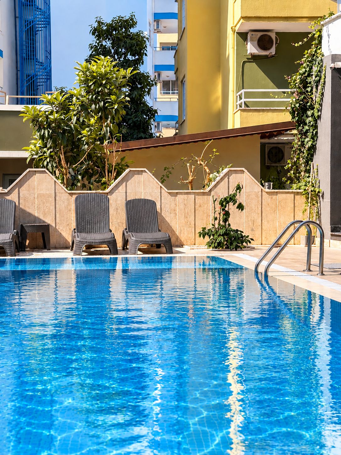 A swimming pool with lounge chairs and a view of a building with balconies.