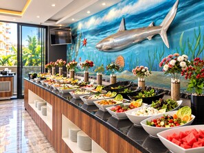 A buffet with various food items and decorative flowers.