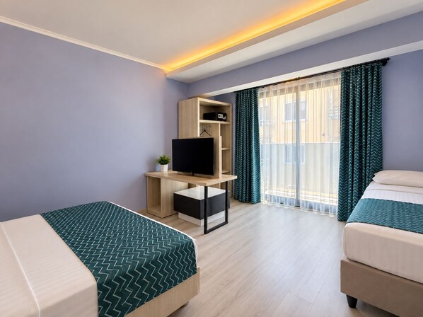 Habitación de hotel con dos camas, un televisor sobre un soporte de madera, una planta pequeña y un balcón con cortinas.