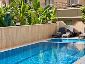 A swimming pool with lounge chairs and tropical plants. - Livaneli Boutique Otel (Alanya)