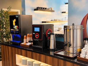 Una estación de café con una máquina de café, un espumador de leche y una jarra de café.