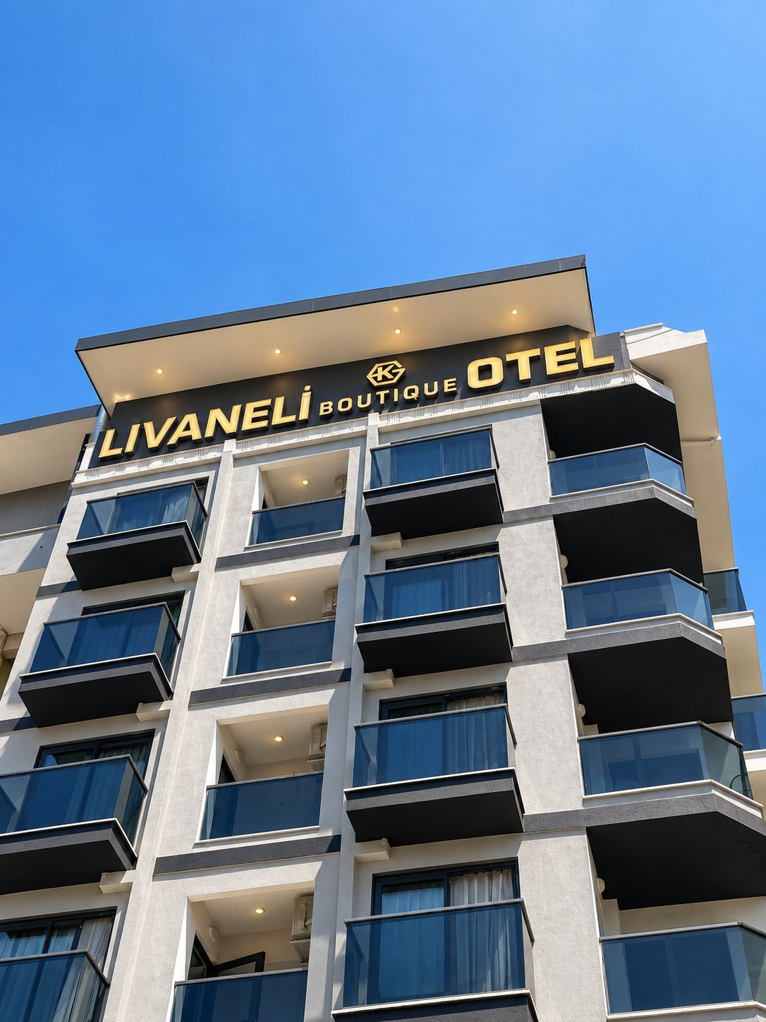 Un edificio de varios pisos con balcones y un letrero que dice 'LIVANELI BOUTIQUE HOTEL'.