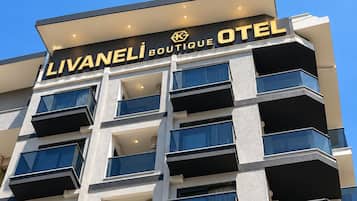 Un edificio de varios pisos con balcones y un letrero que dice 'LIVANELI BOUTIQUE HOTEL'.