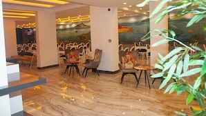 A modern interior with a seating area featuring chairs and tables, a mural with marine life, and a polished marble floor. - Livaneli Boutique Otel (Alanya)