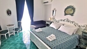 Ein Schlafzimmer mit Bett, Stuhl, kleinem Tisch und Spiegel.