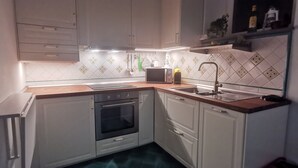 Eine moderne Küche mit weißen Schränken, einem eingebauten Backofen, einer Mikrowelle und einem Spülbecken.