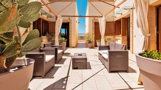 An outdoor patio with wicker furniture, a large umbrella, and potted plants. - 2059 Lido Marini Rooms -Tripla (Salve)