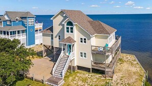 Une maison située sur la côte, dotée d’un balcon, d’un escalier menant à l’entrée principale et offrant une vue sur la mer.