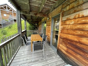 Une terrasse en bois avec une table et des chaises, une porte vitrée et une rambarde en bois.