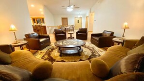A living room with a round coffee table, leather sofas, and a patterned rug. - Sleeps 15 Beautiful Home on 1.2 Acre lot Minutes from Lakes, boat dock & beach (Albert Lea)