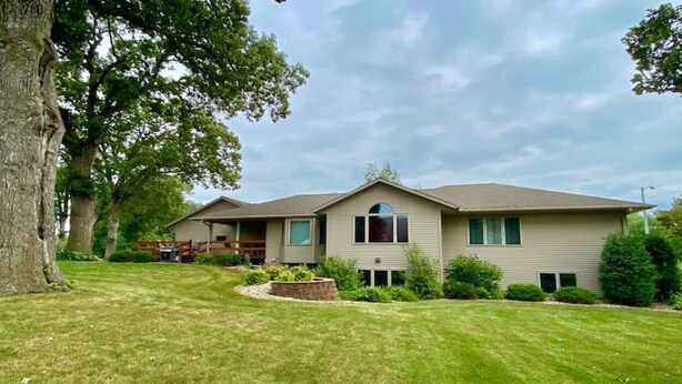 A two-story house with a front porch, a garage, and a well-maintained lawn. - Sleeps 15 Beautiful Home on 1.2 Acre lot Minutes from Lakes, boat dock & beach (Albert Lea)