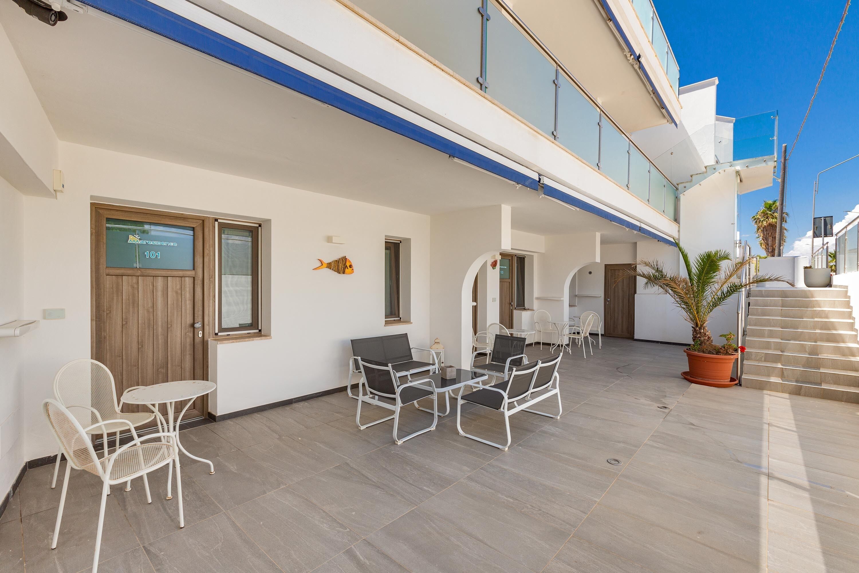 A modern outdoor patio with a dining area, a wooden door, and a potted plant.